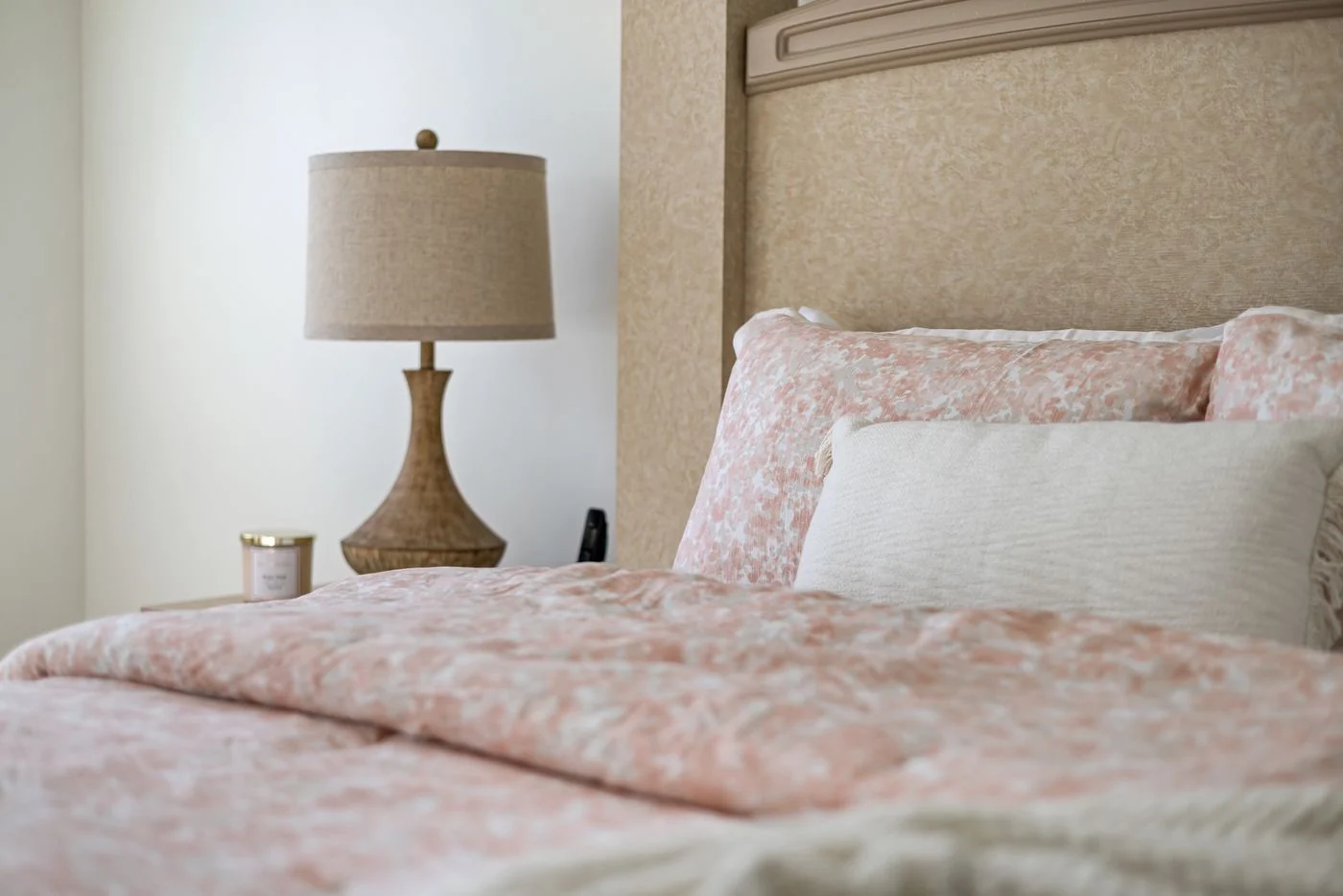 A peaceful bedroom setup with soft bedding and warm bedside lamp lighting.