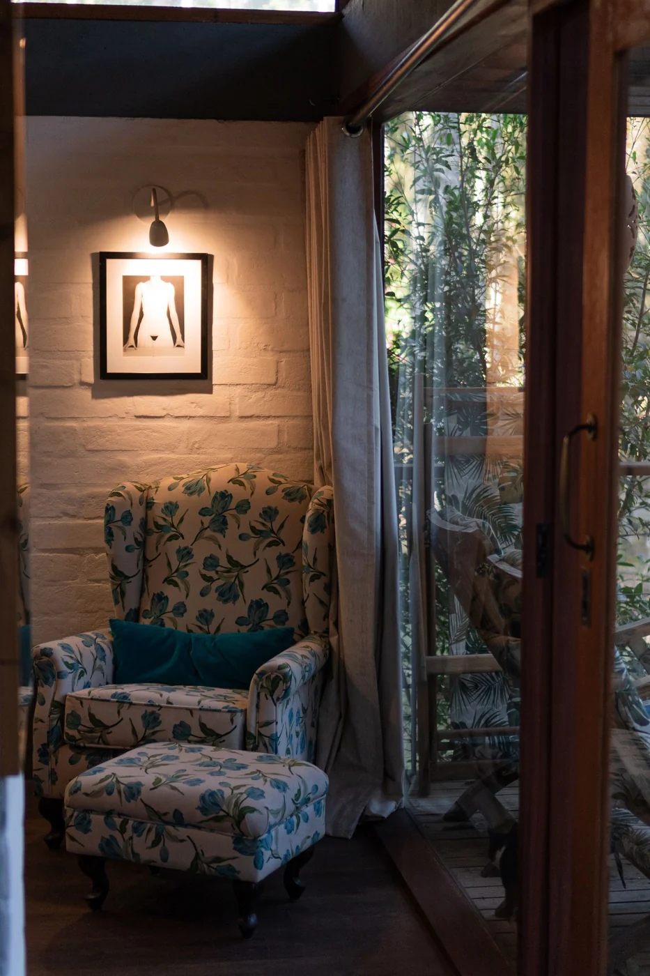 Inviting reading corner featuring a floral armchair, lit by soft interior light next to a large window.