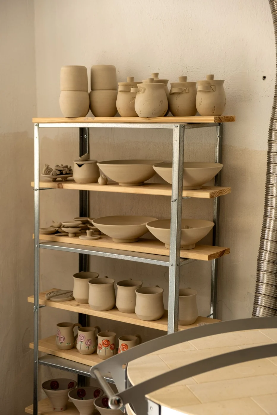 Shelves filled with handcrafted pottery and clay containers in a cozy studio setting.