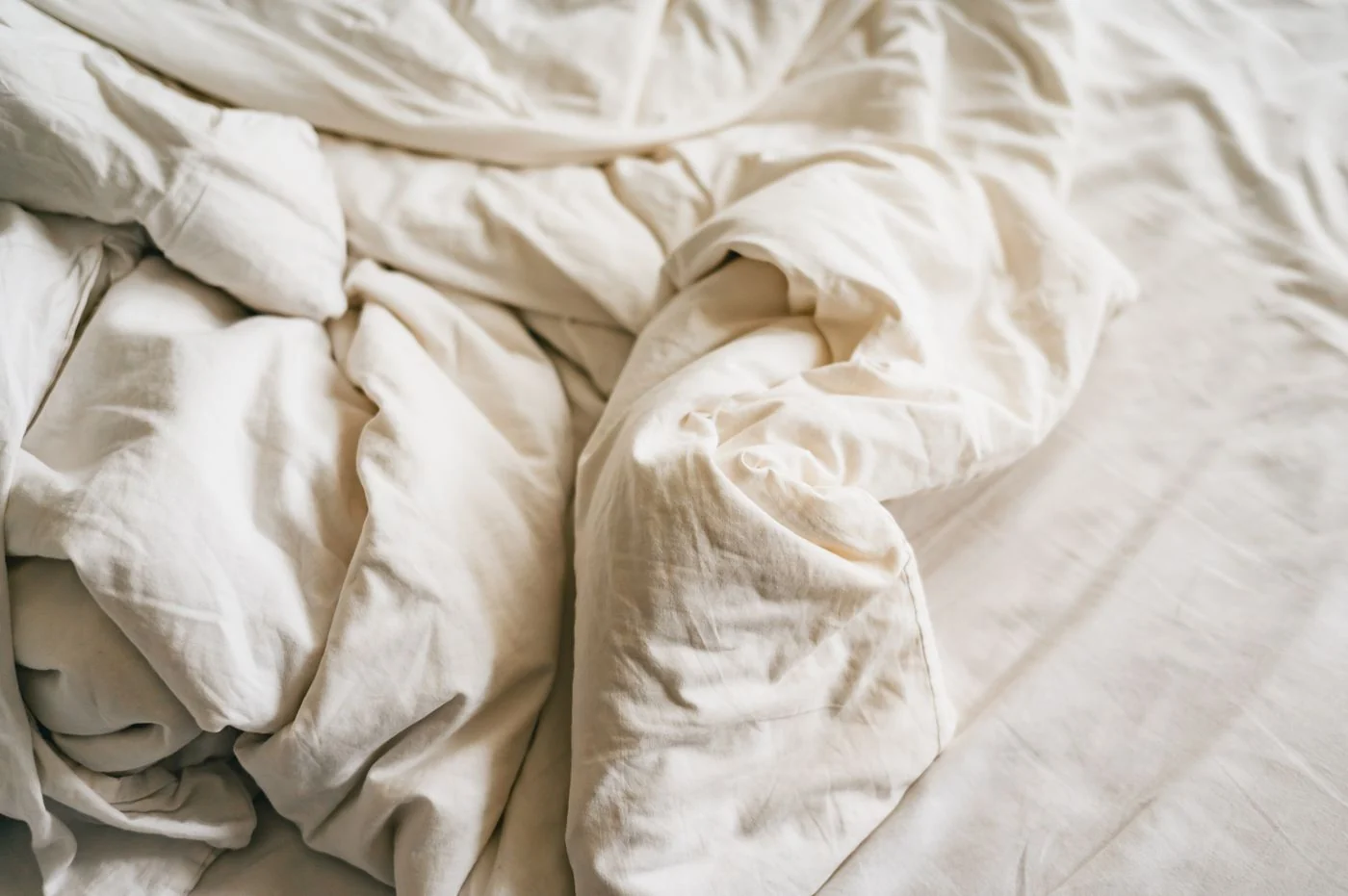 A close-up of cozy and wrinkled white linen bedding, conveying comfort and relaxation.