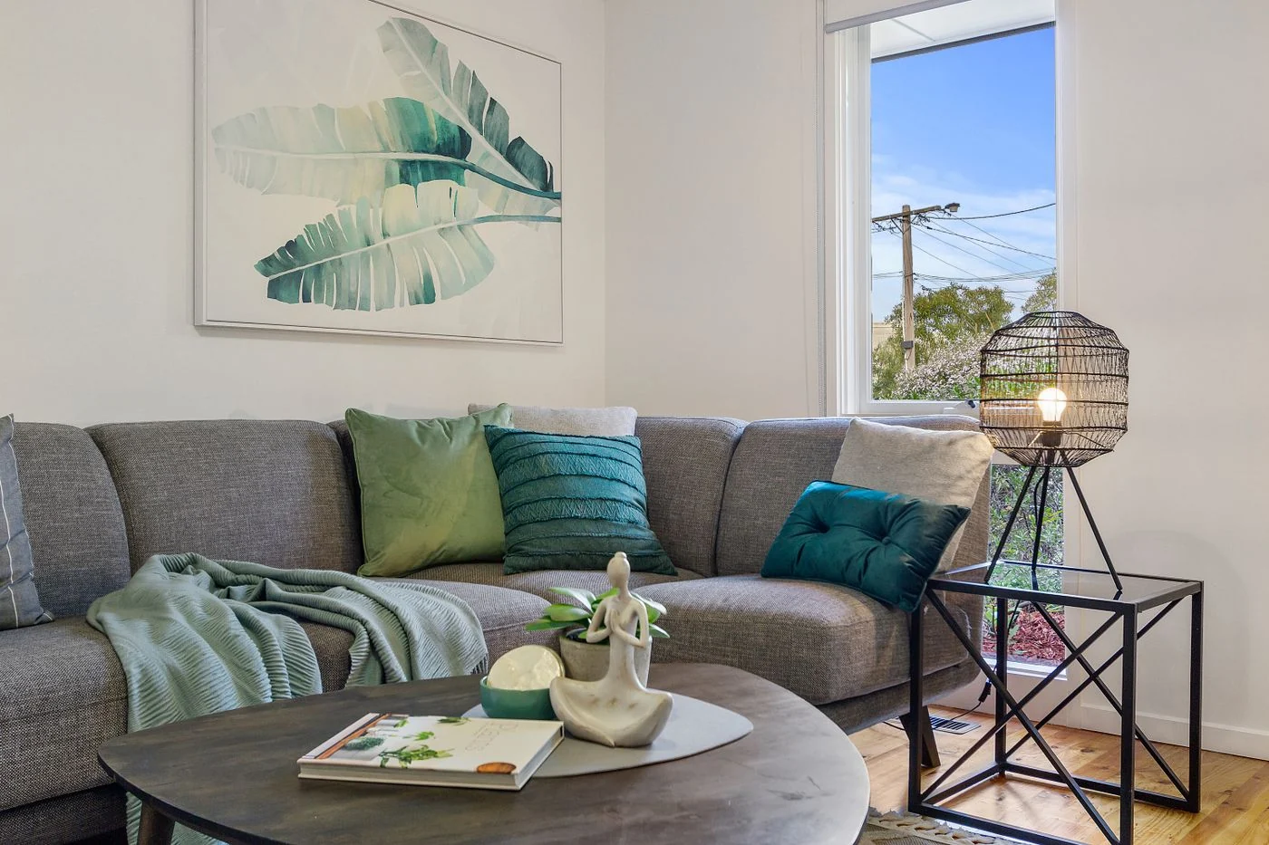 A stylish living room featuring a gray sofa, decorative cushions, and a modern lamp.