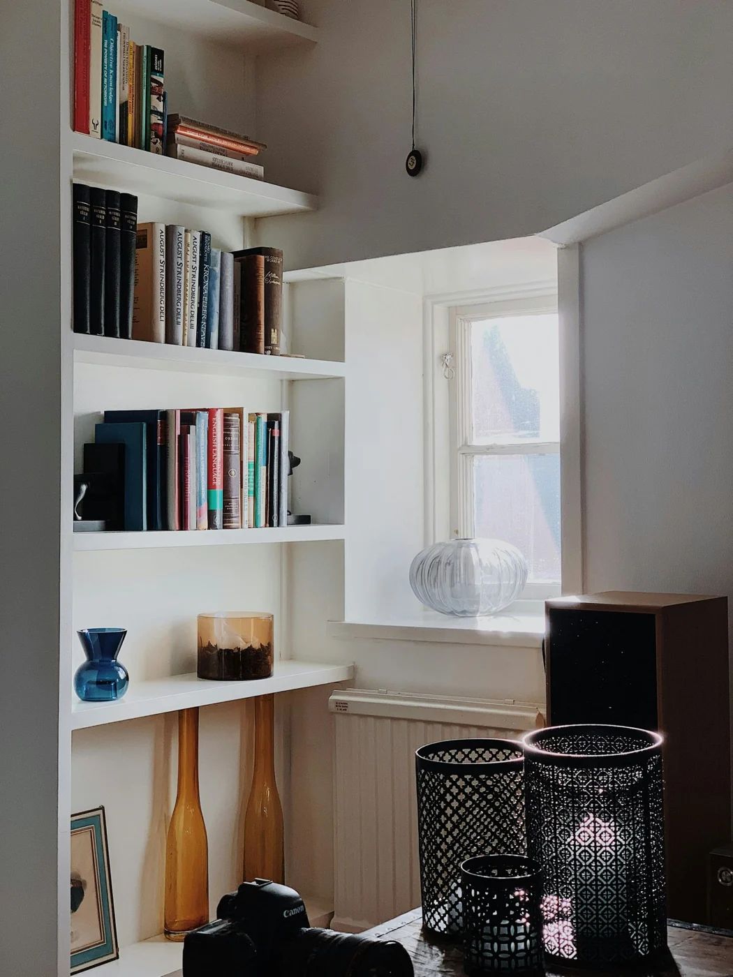 A charming and well-lit reading nook in a Stockholm home featuring a shelf full of books and decorative items.
