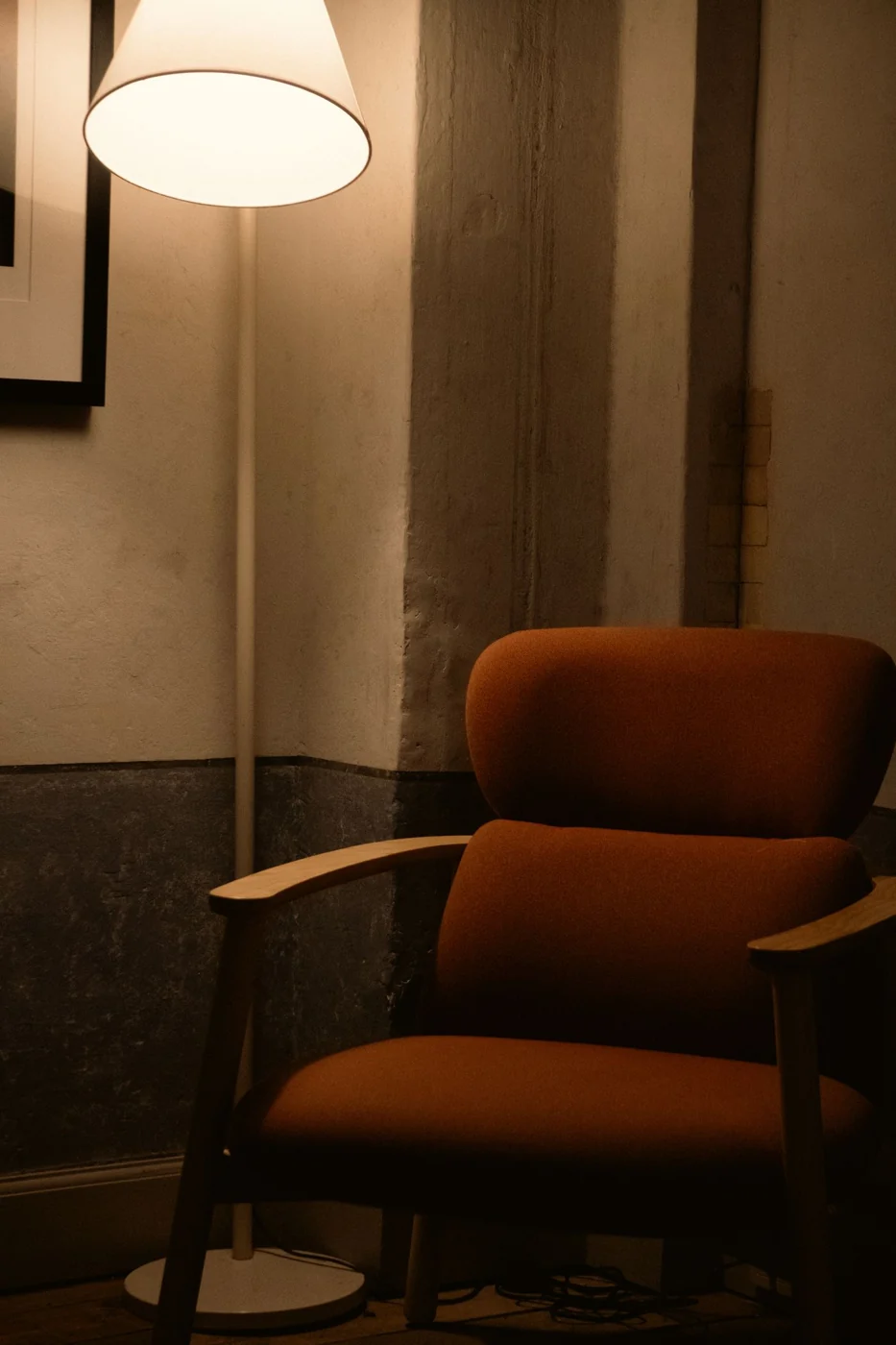 A warm and inviting corner featuring a lamp and an armchair, perfect for relaxation.