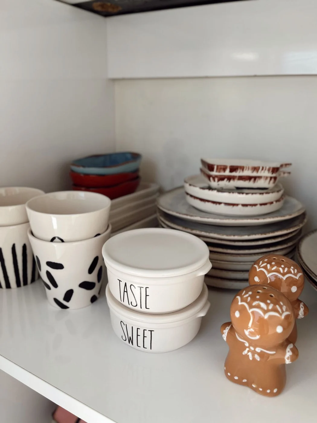 Neat kitchen shelf with plates, bowls, and gingerbread decor.