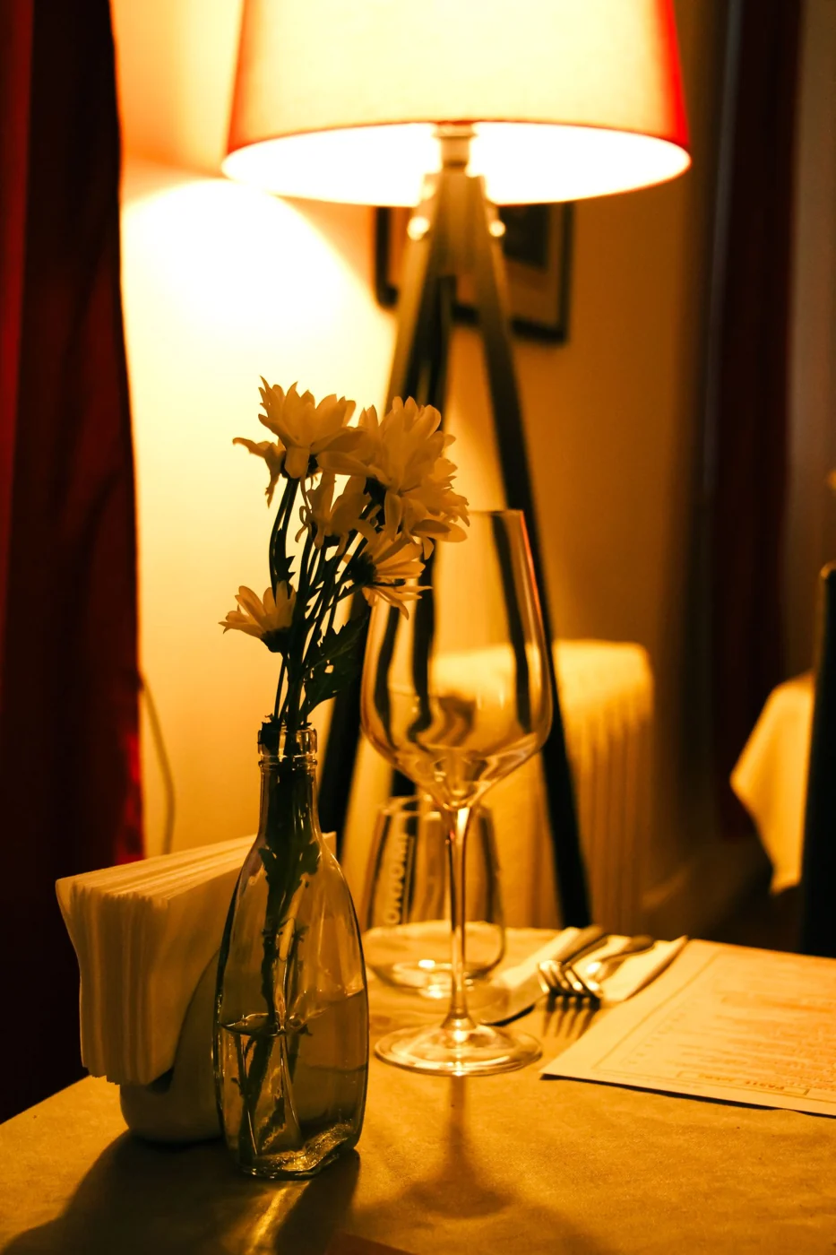 Warm and intimate table setup with flowers, wine glass, and soft lighting, perfect for a romantic dinner.