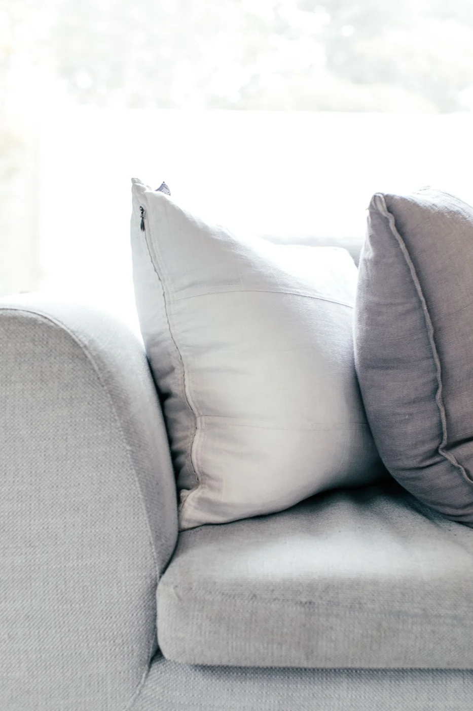 Modern gray sofa with cushions in a serene, minimalist living room setting.