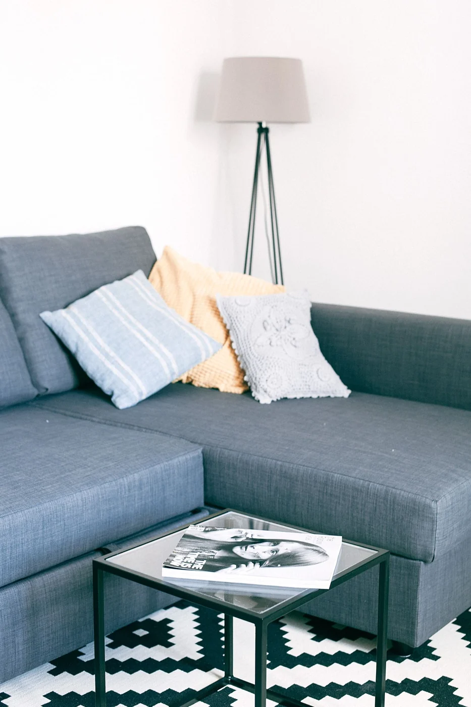 A minimalist living room featuring a comfortable sofa, cushions, and stylish decor.