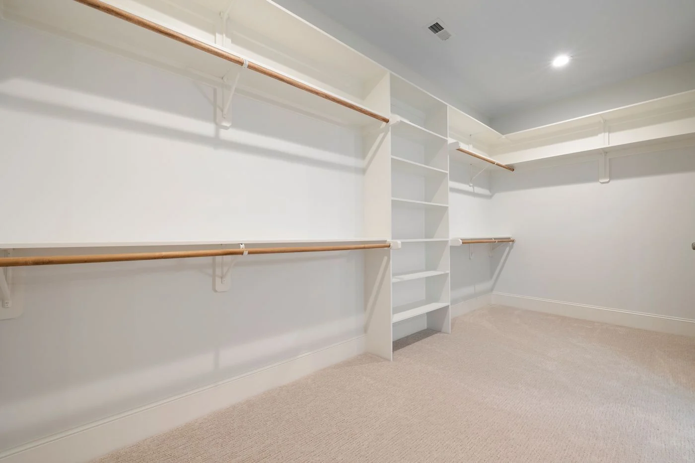 Modern empty walk-in closet with ample shelves and hanging rods for storage.