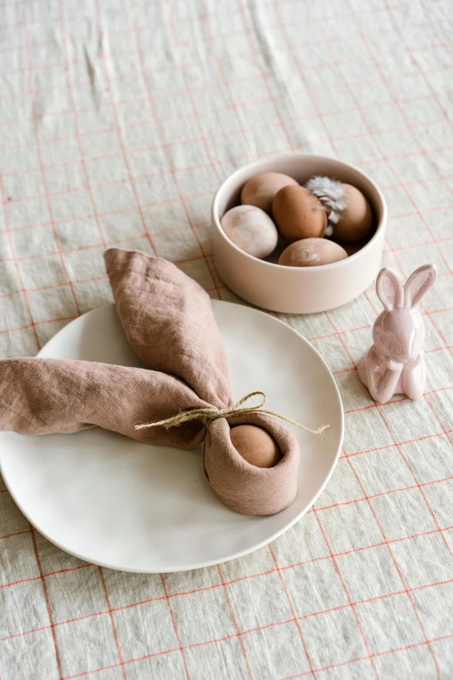Chic Easter table decor featuring eggs and a decorative bunny on a linen tablecloth.