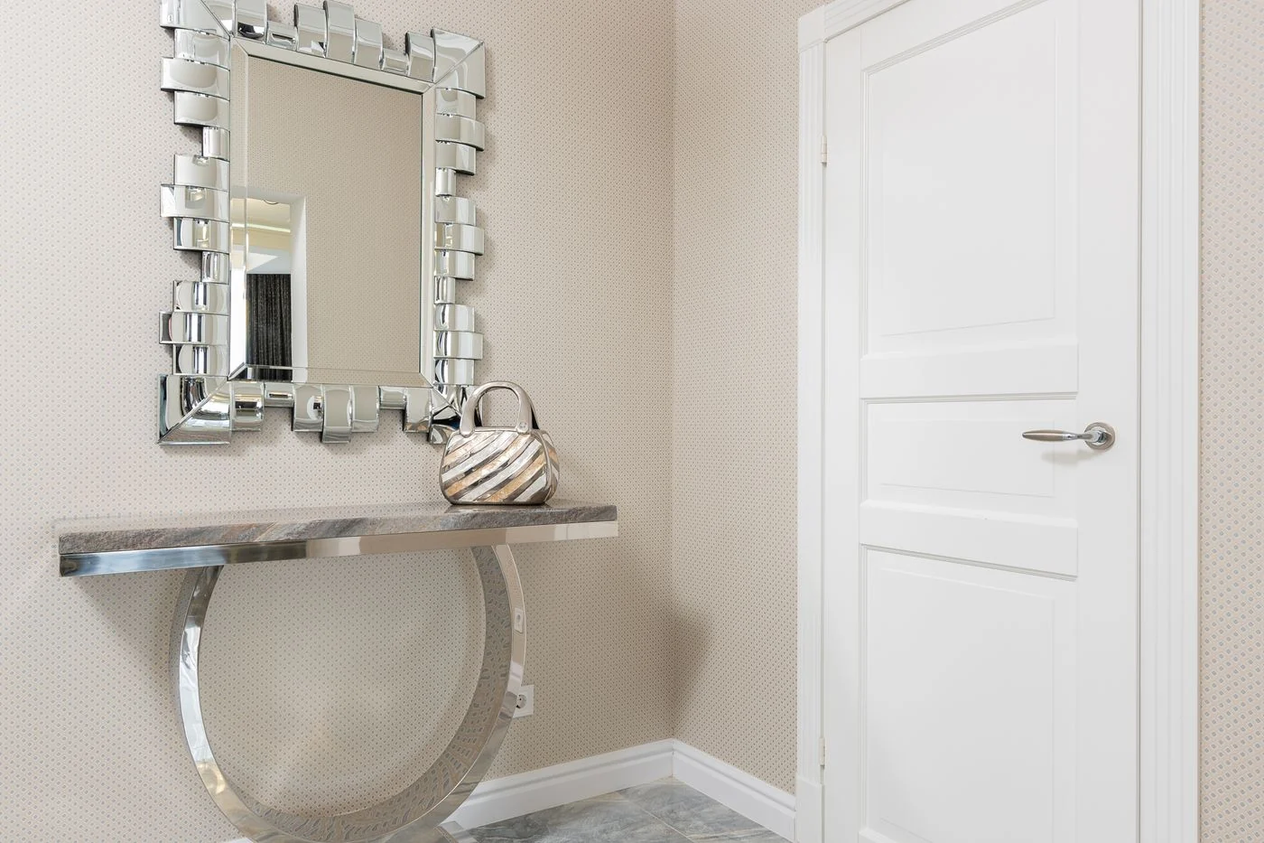 Sleek modern entryway featuring a decorative mirror, metallic console, and stylish handbag.