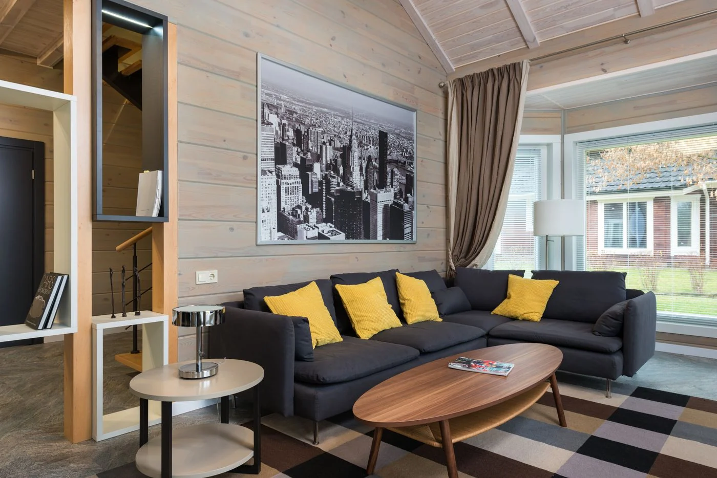 Contemporary living room with a gray sofa, yellow cushions, and a cityscape artwork.