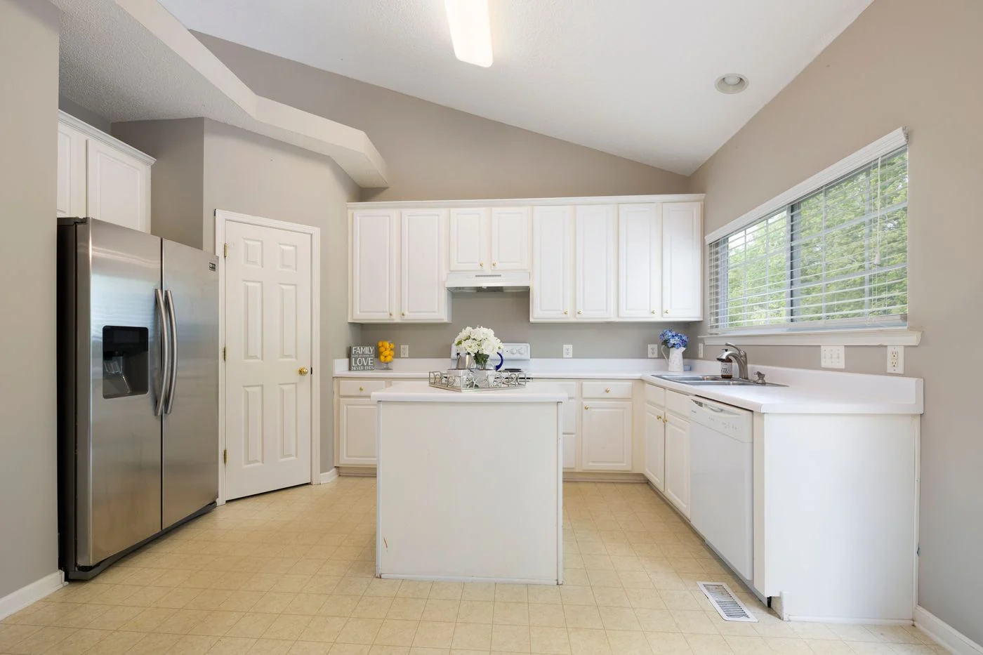 Bright white kitchen showcasing modern cabinets, island, and stainless steel appliances.