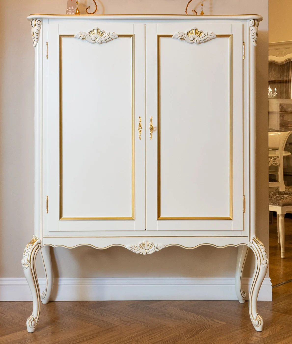 Classic vintage white armoire with ornate details in a cozy interior setting.